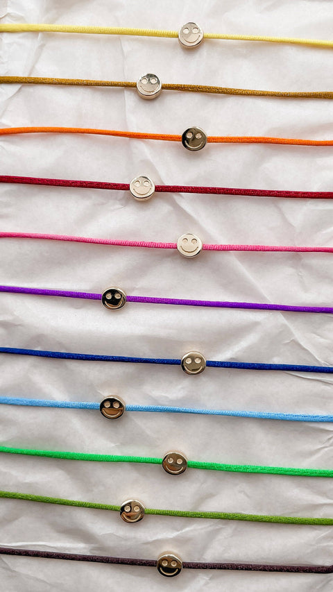 Set of colorful bracelets with gold smiley bead.