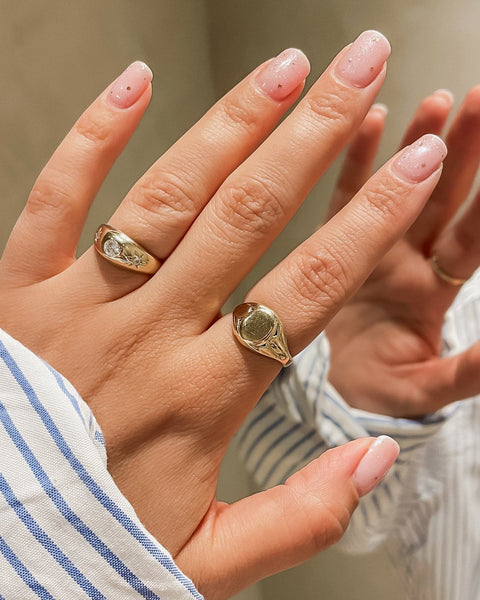 Close-up of a hand wearing two gold rings with a blurred background