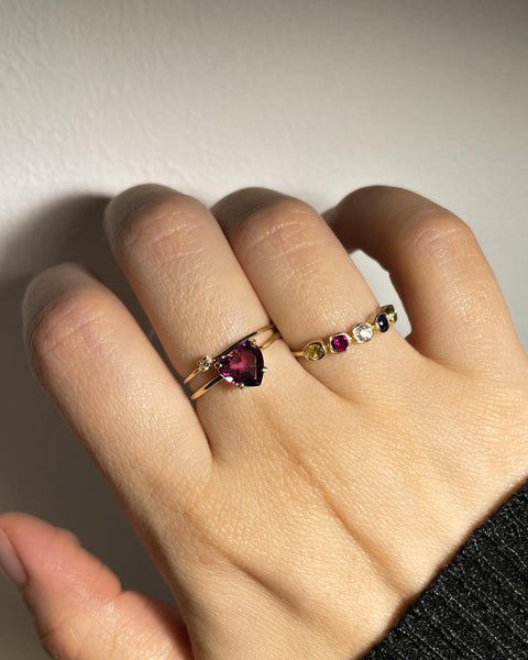 Rhodolite Heart Ring made from Recycled 14k Solid Yellow Gold with a Glossy Polished Surface on a 0.9mm Signature Fine Wire Band. Ring party featuring the Rhodolite Heart Ring on a hand.