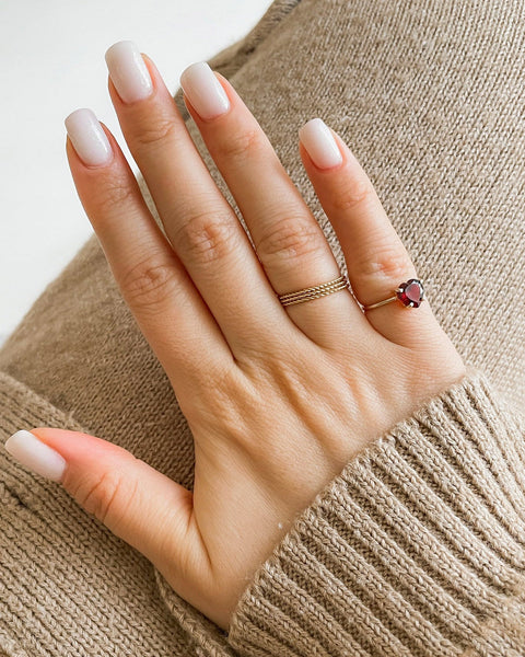 Close-up of a hand with two rings on a beige sweater