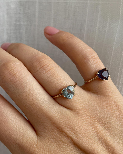 Recycled solid 14k yellow gold ring with 7mm Aquamarine & Iolite Heart on 0.9 mm fine wire band, featuring a glossy polished surface. Hand showcasing ring in a ringparty setting.